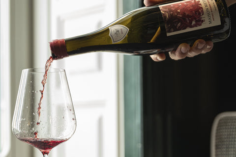 Vino tinto de Maison Meyer, de Borgoña, cayendo en una copa junto a una ventana con luz natural