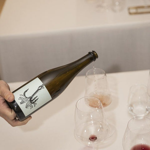 Botella de vino de un productor de Vins Des Dieux servida en la mesa de un restaurante
